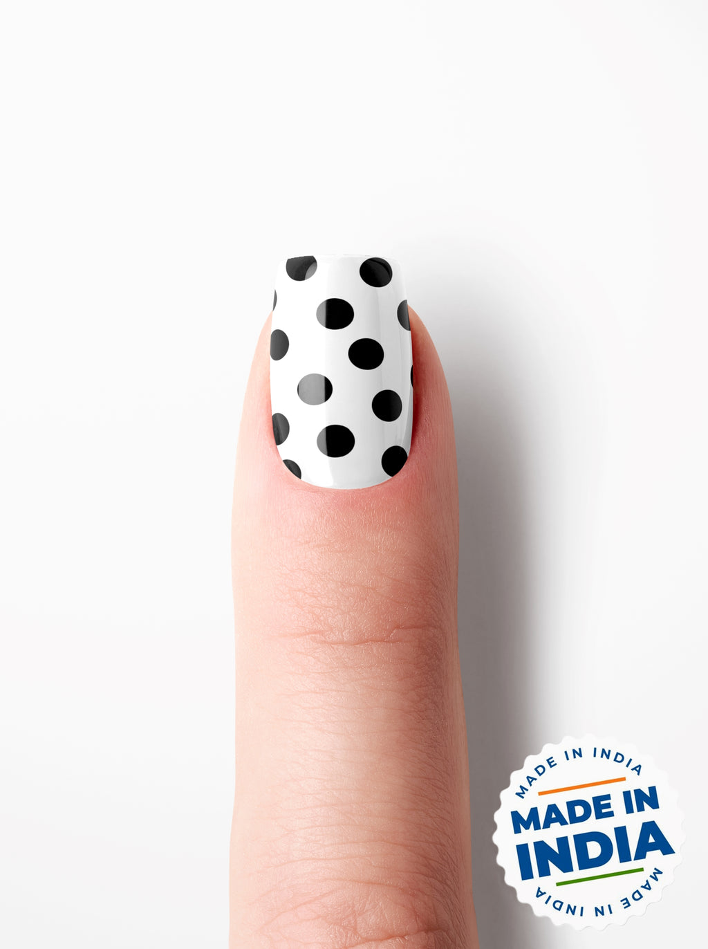 Finger with black and white polka dot nail polish on a white background with 'Made in India' label.