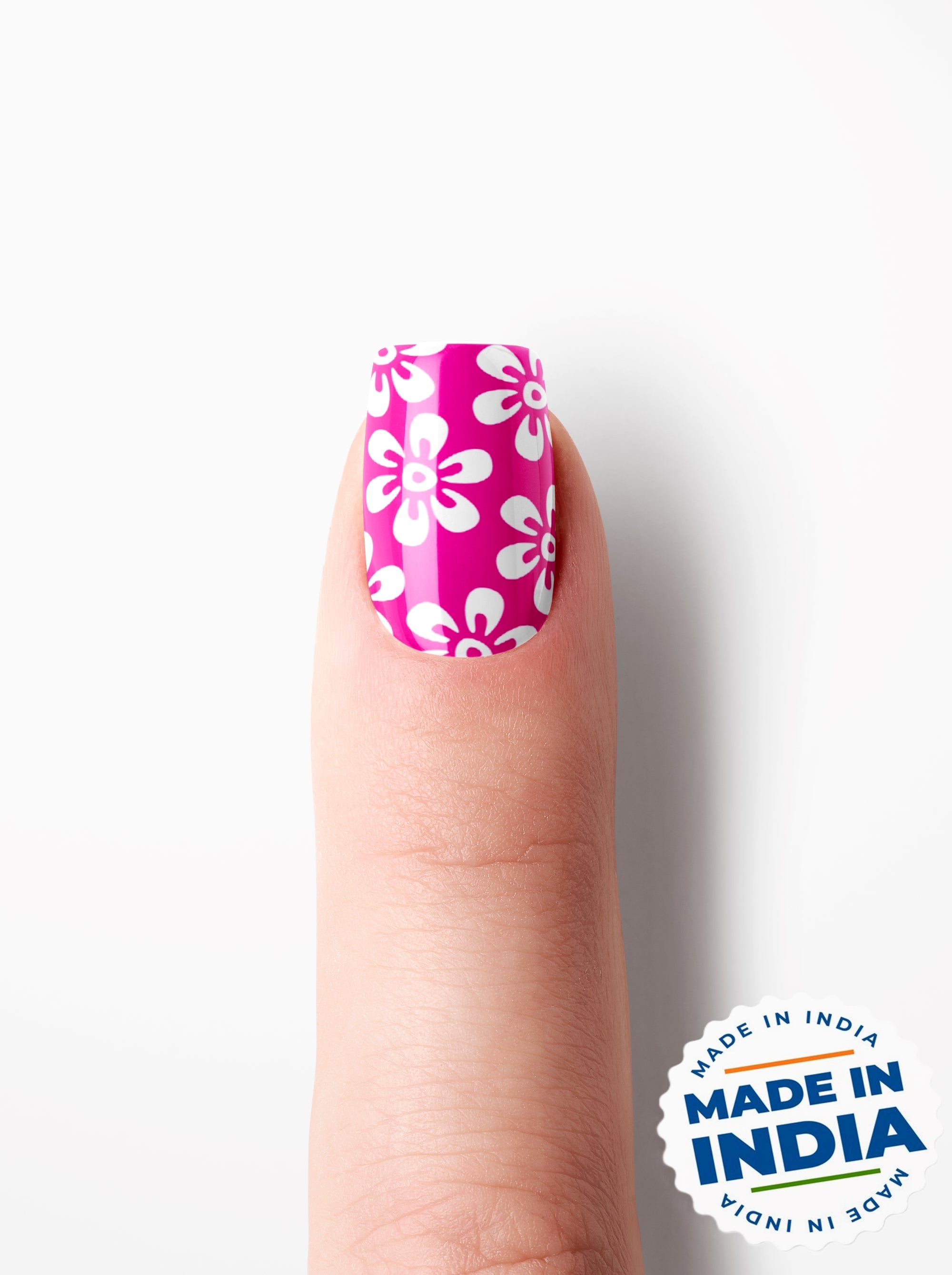 Finger with pink nail polish with white floral design on a white background, featuring 'Made in India' label.