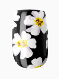 Black nail wrap with white flowers and yellow centers on a white background